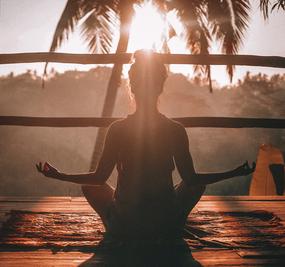 Backpain - A lady meditating facing sunrise