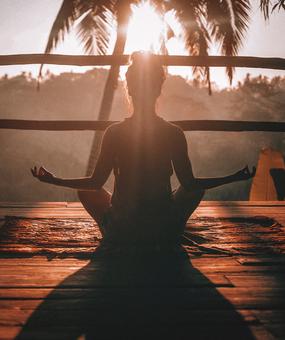 Backpain - A lady meditating facing sunrise